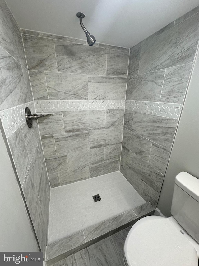 bathroom with a tile shower and toilet