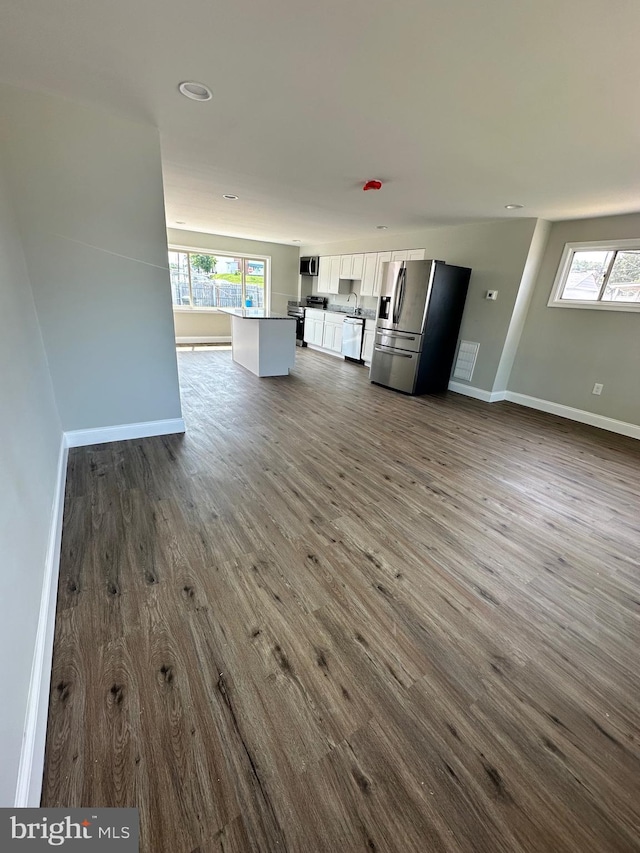 unfurnished living room featuring dark wood-type flooring and a healthy amount of sunlight