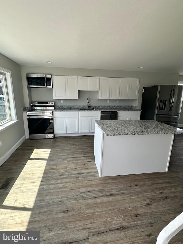 kitchen with white cabinetry, light stone countertops, dark wood-type flooring, sink, and stainless steel appliances