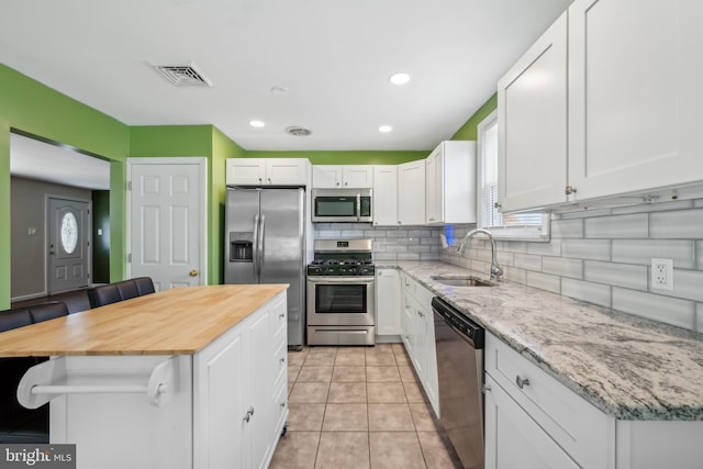 kitchen featuring white cabinets, appliances with stainless steel finishes, sink, and a breakfast bar area