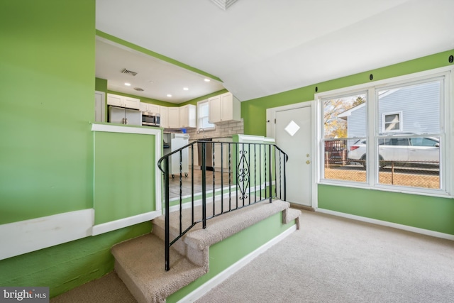 stairs featuring carpet and sink