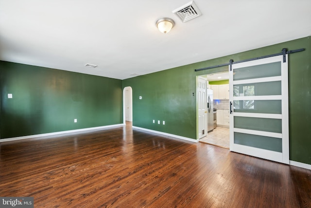 empty room featuring a barn door and hardwood / wood-style flooring