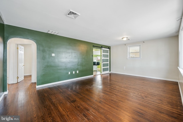 spare room featuring dark hardwood / wood-style flooring and a barn door