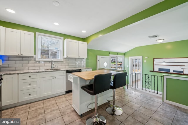 kitchen with white cabinetry, sink, light stone counters, backsplash, and stainless steel dishwasher