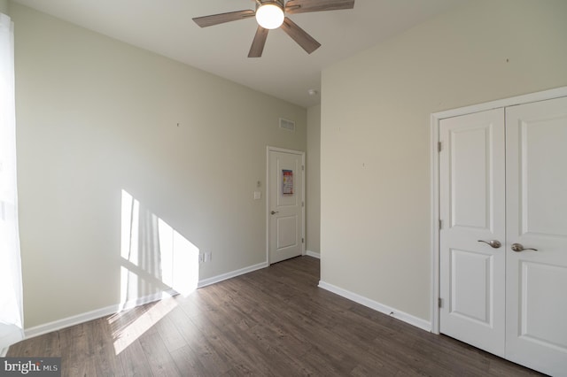 unfurnished bedroom featuring dark wood-type flooring, a closet, and ceiling fan