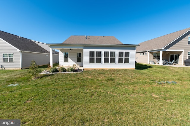 rear view of property featuring ceiling fan, a yard, and a patio area