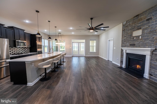 kitchen featuring appliances with stainless steel finishes, a breakfast bar area, decorative light fixtures, a large island, and dark hardwood / wood-style flooring