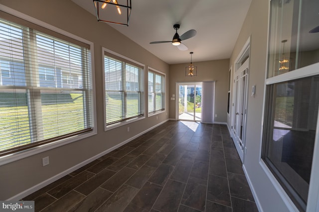 unfurnished sunroom featuring ceiling fan with notable chandelier