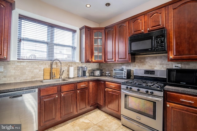 kitchen with appliances with stainless steel finishes, tasteful backsplash, sink, and light tile patterned floors