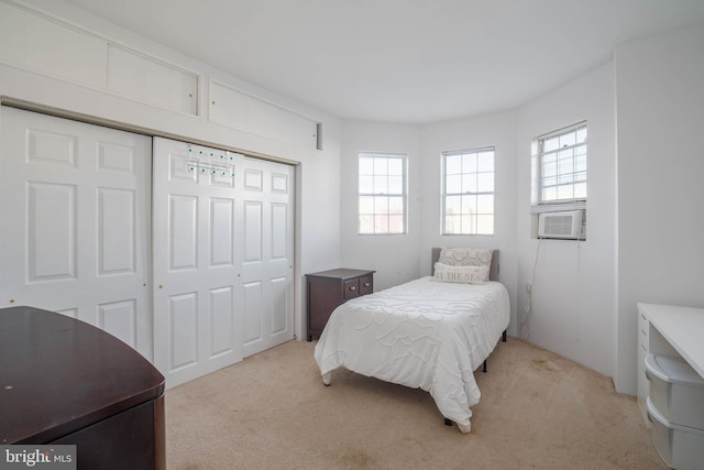 bedroom with cooling unit, light carpet, and a closet