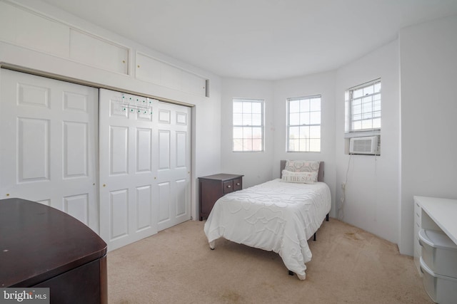 bedroom featuring light carpet, multiple windows, cooling unit, and a closet