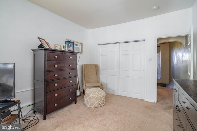 sitting room featuring arched walkways and light colored carpet