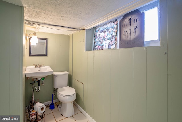 bathroom with toilet, wood walls, a textured ceiling, and tile patterned flooring