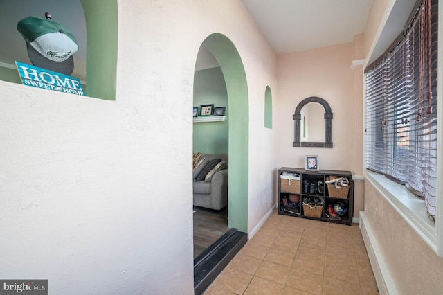 hall with arched walkways and tile patterned flooring