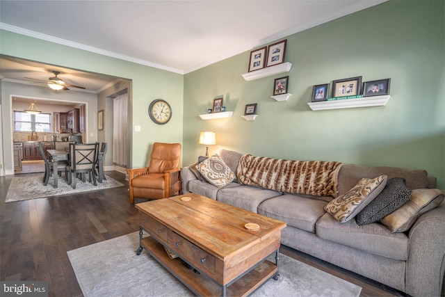 living area featuring ceiling fan, baseboards, crown molding, and wood finished floors