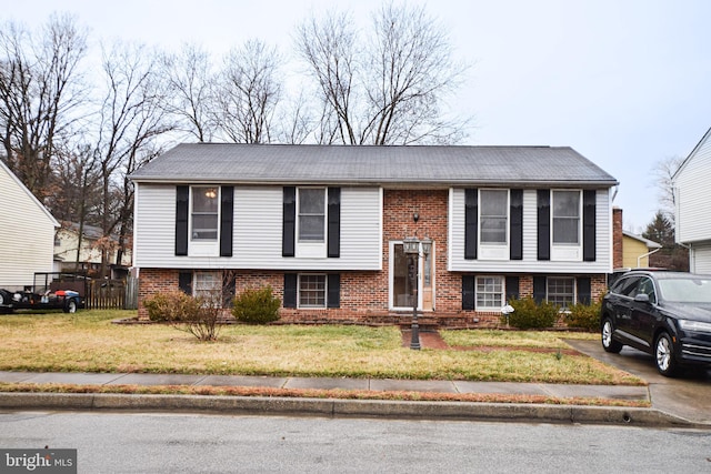 bi-level home with brick siding, a front lawn, and fence