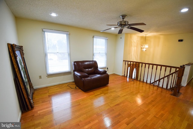 living area featuring a textured ceiling, recessed lighting, baseboards, and light wood-style floors