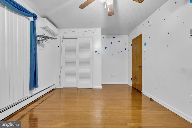 unfurnished room featuring ceiling fan, a baseboard heating unit, a wall unit AC, and hardwood / wood-style floors