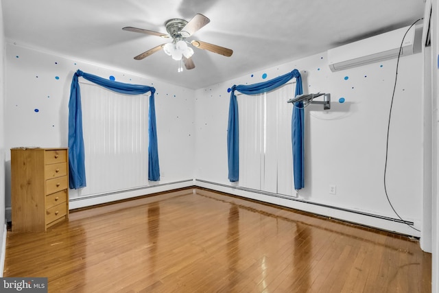 spare room featuring hardwood / wood-style flooring, an AC wall unit, baseboard heating, and ceiling fan