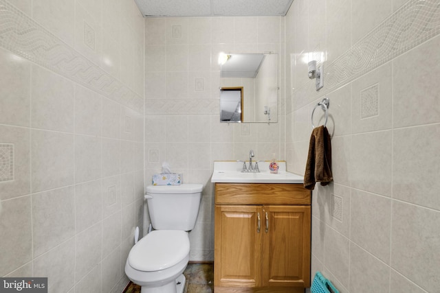 bathroom with vanity, toilet, tile walls, and a textured ceiling