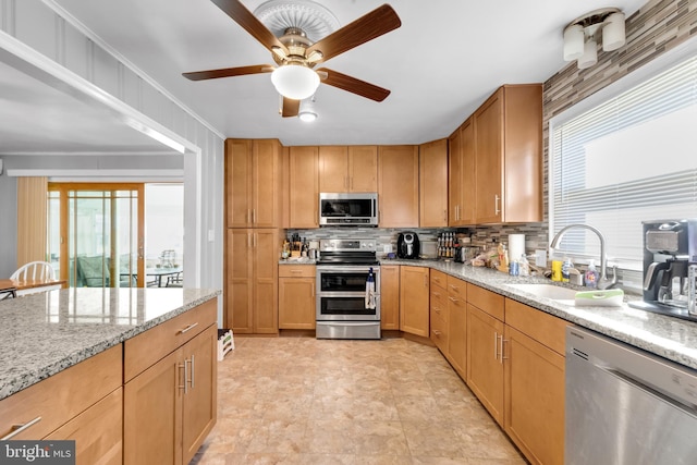 kitchen with decorative backsplash, light stone counters, ceiling fan, sink, and stainless steel appliances