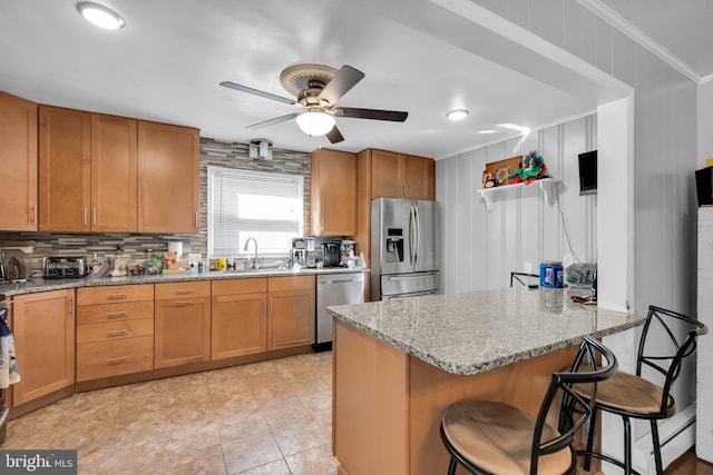 kitchen featuring appliances with stainless steel finishes, a kitchen breakfast bar, sink, crown molding, and light stone counters