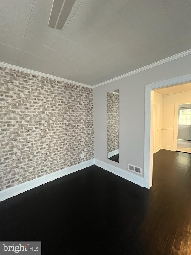 unfurnished room with brick wall, ornamental molding, and dark hardwood / wood-style floors