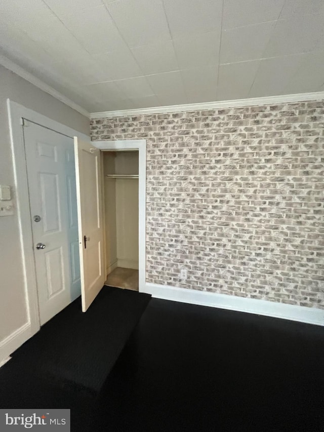 interior space with brick wall, crown molding, and a closet