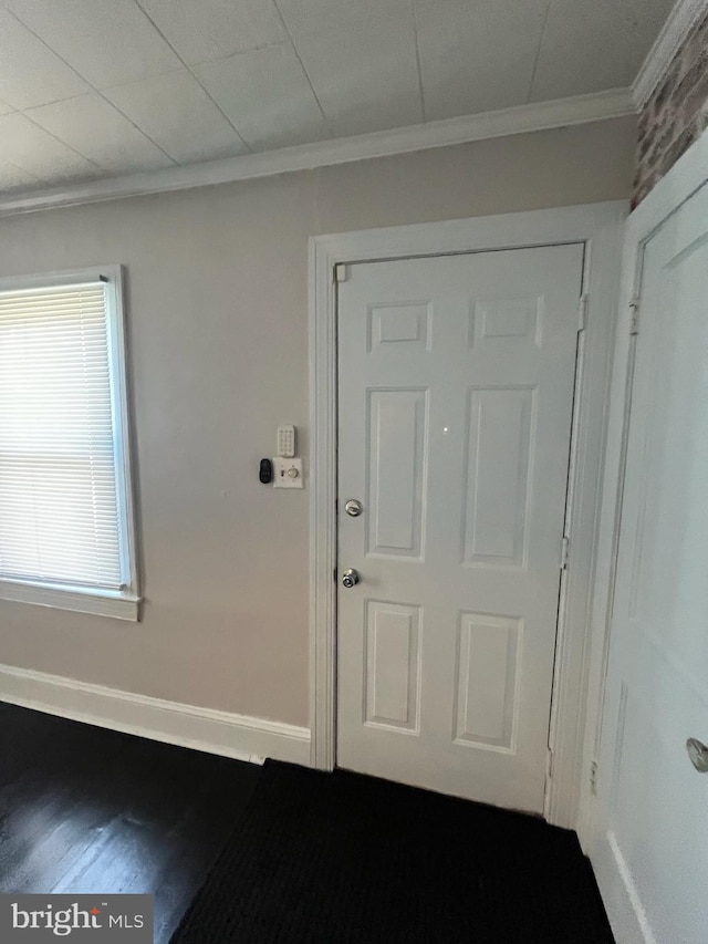 entryway with ornamental molding and hardwood / wood-style floors