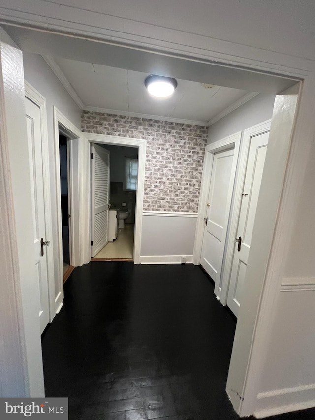 hallway featuring ornamental molding, hardwood / wood-style floors, and brick wall