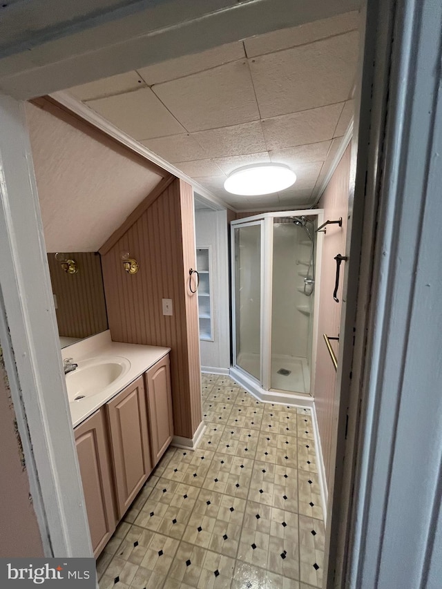 bathroom with vanity, a shower with shower door, and wooden walls