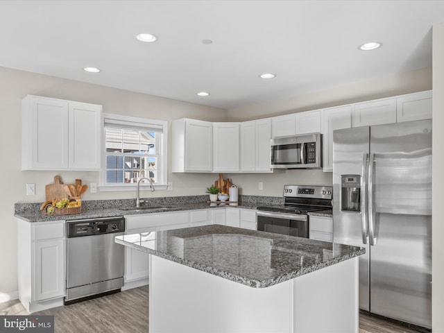 kitchen with a kitchen island, white cabinets, and stainless steel appliances