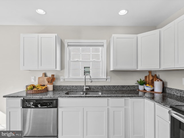 kitchen featuring appliances with stainless steel finishes, white cabinets, dark stone countertops, and sink