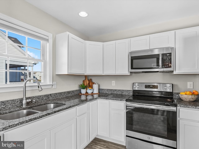 kitchen featuring sink, appliances with stainless steel finishes, white cabinetry, and dark stone counters