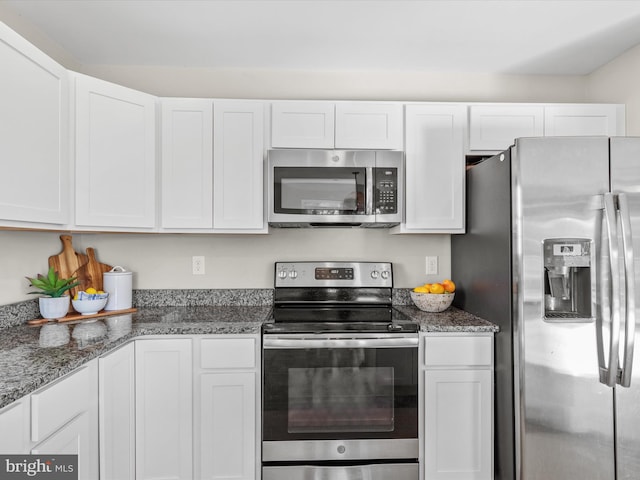 kitchen featuring white cabinetry, stainless steel appliances, and dark stone countertops