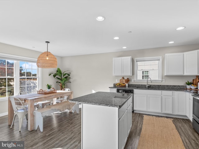 kitchen with dark wood-type flooring, sink, a center island, decorative light fixtures, and white cabinetry