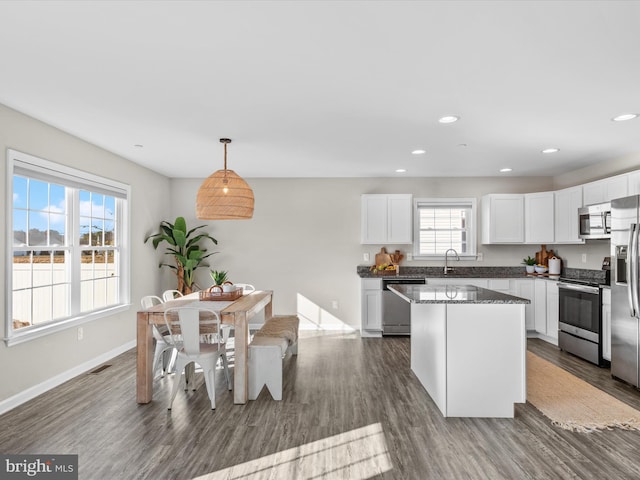 kitchen featuring a healthy amount of sunlight, white cabinets, stainless steel appliances, and hanging light fixtures