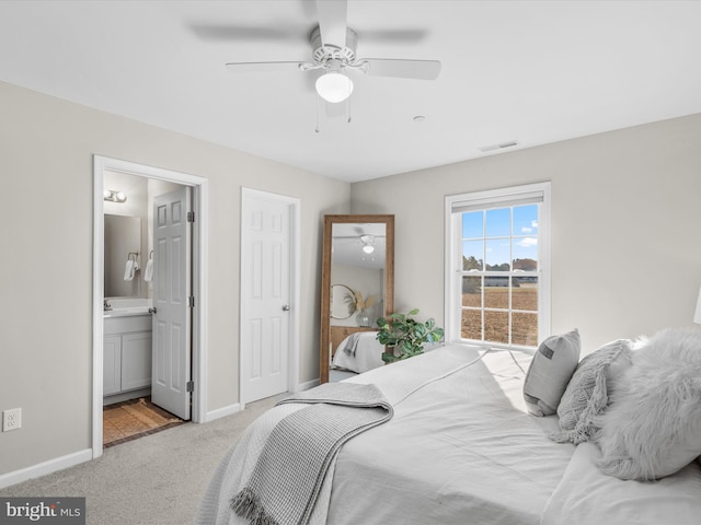 carpeted bedroom with ceiling fan and ensuite bath