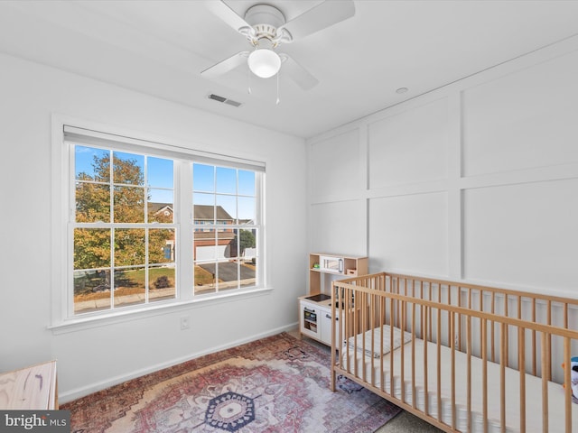 bedroom with a crib and ceiling fan