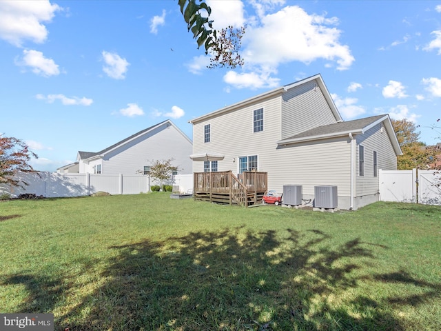 rear view of house with cooling unit, a deck, and a lawn