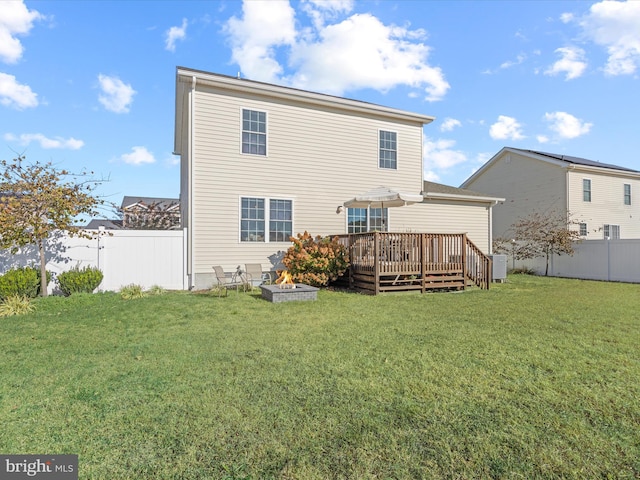 back of house featuring an outdoor fire pit, a deck, and a lawn