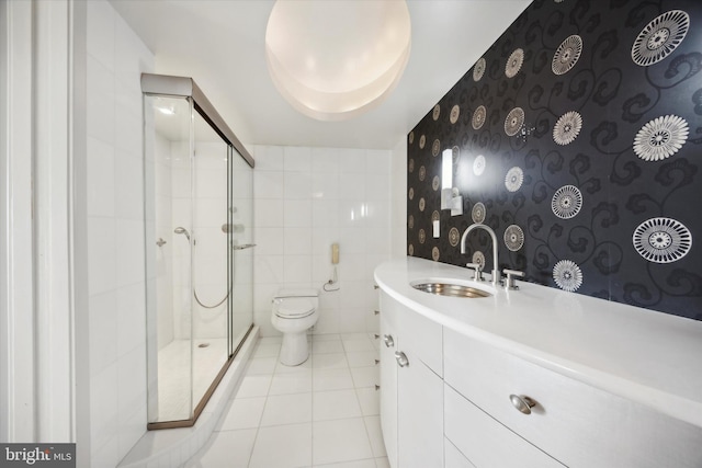 bathroom with tile walls, tile patterned floors, vanity, toilet, and a shower with shower door