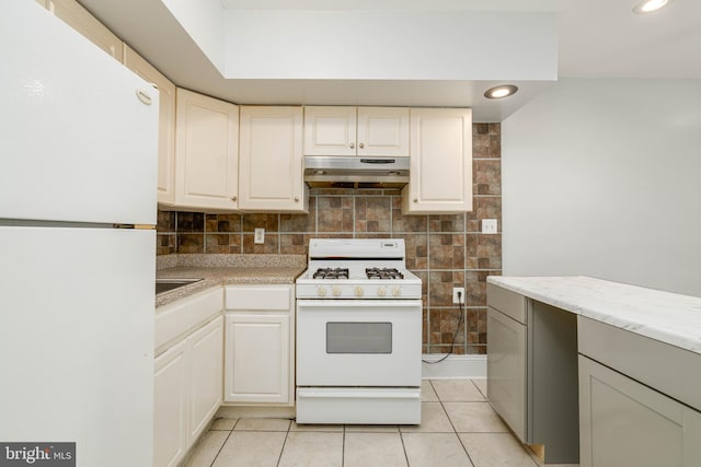 kitchen with white cabinets, tasteful backsplash, light tile patterned flooring, and white appliances