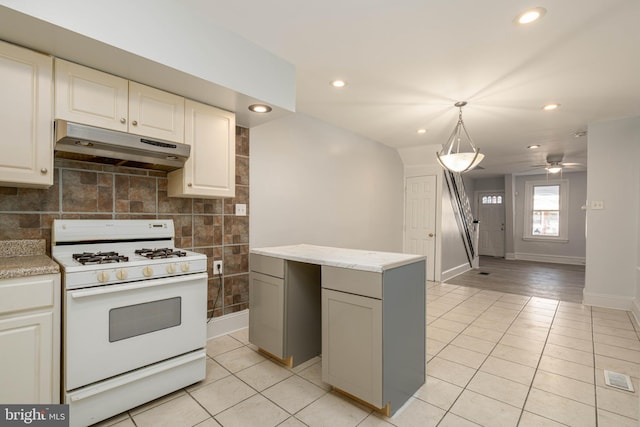 kitchen with a kitchen island, white range with gas cooktop, pendant lighting, light tile patterned floors, and ceiling fan