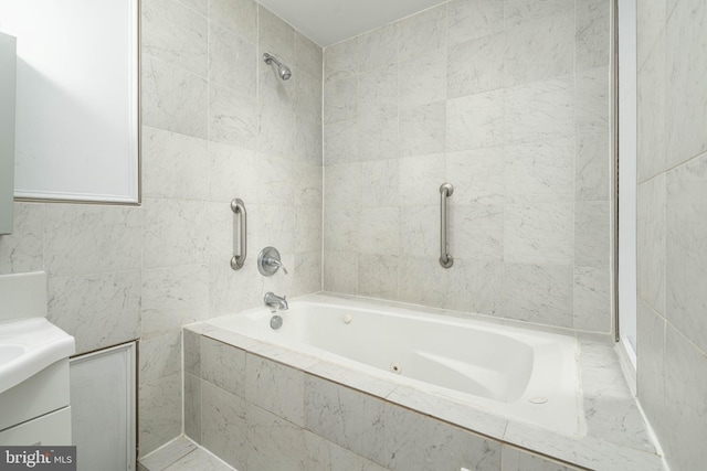 bathroom with tiled shower / bath, vanity, and tile walls