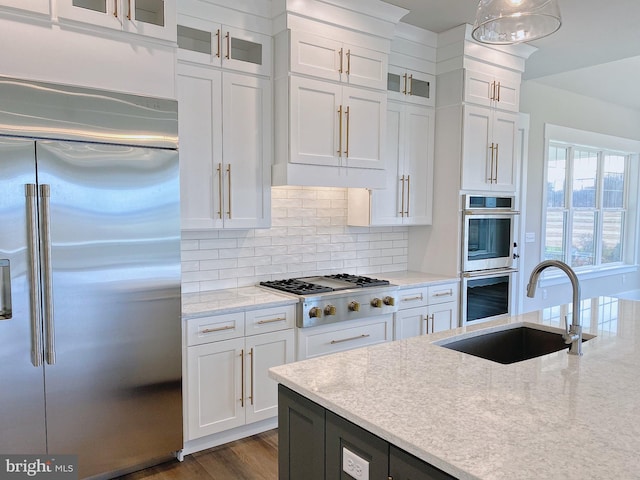 kitchen featuring decorative light fixtures, white cabinets, stainless steel appliances, and sink