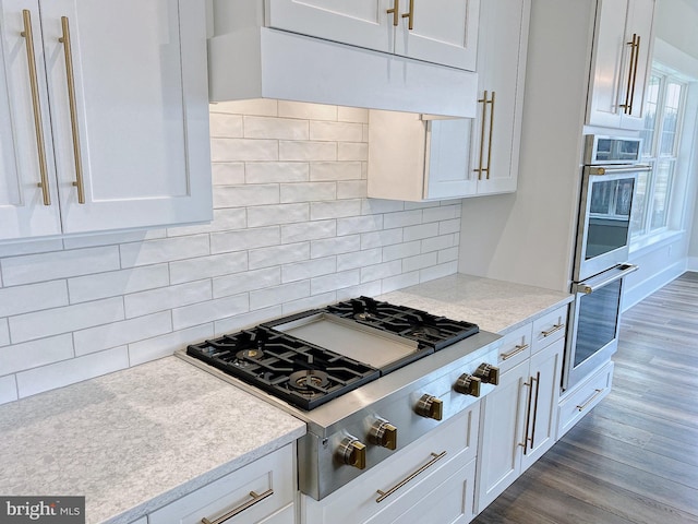 kitchen with appliances with stainless steel finishes, tasteful backsplash, white cabinetry, and dark hardwood / wood-style flooring