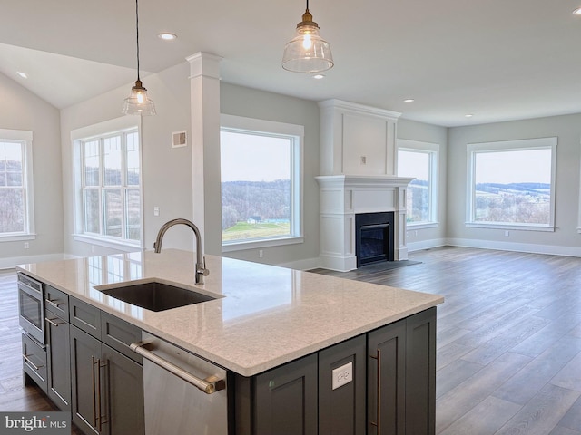 kitchen featuring sink, dishwasher, decorative light fixtures, dark wood-type flooring, and light stone counters