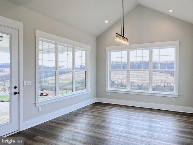 unfurnished dining area featuring dark wood-type flooring, high vaulted ceiling, and a chandelier