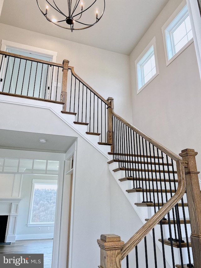 stairway featuring hardwood / wood-style floors, a chandelier, and a high ceiling